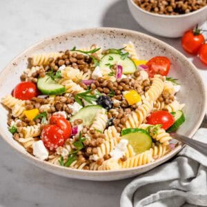 Lentil pasta salad in a bowl tossed with dressing.