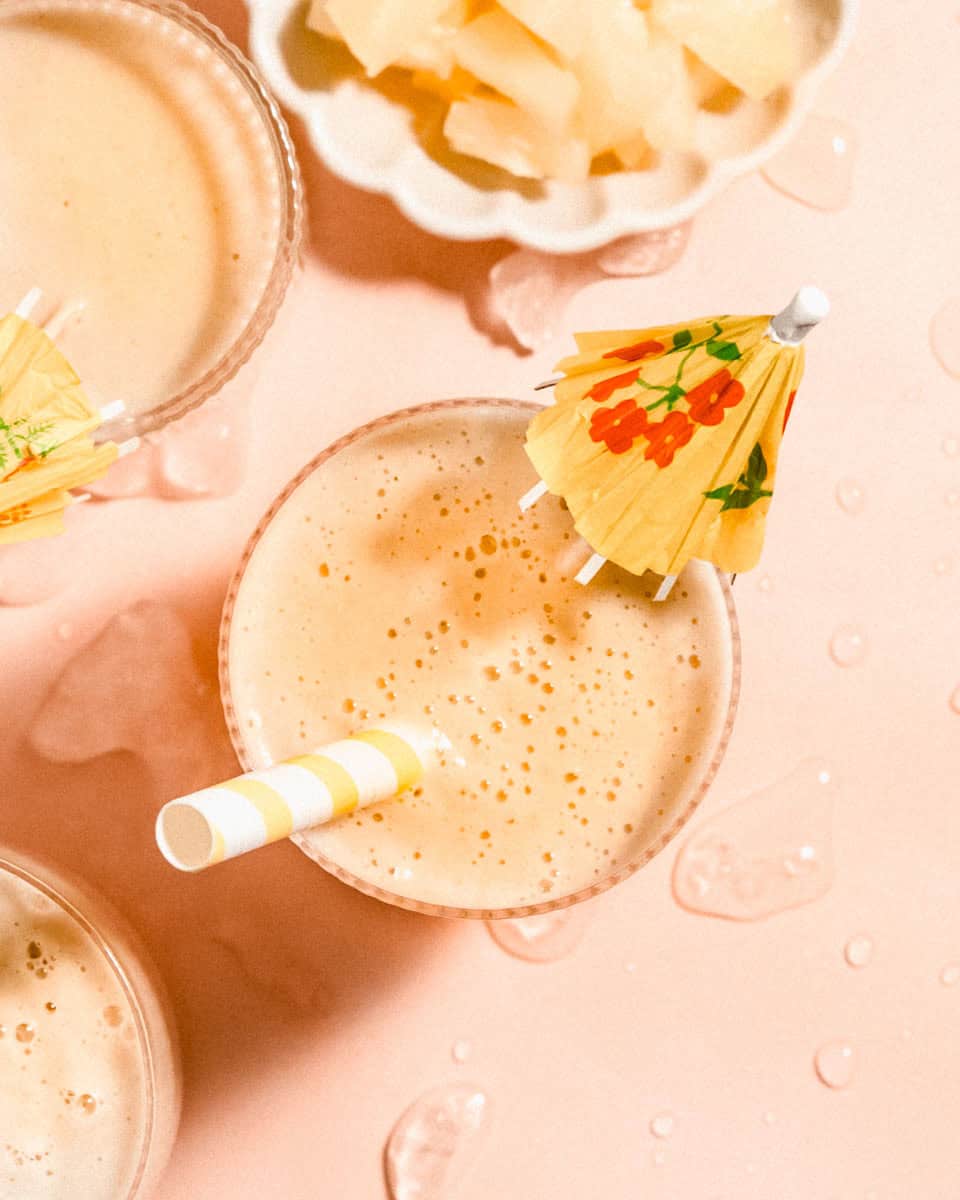 Birds eye view of 3 glasses of smoothie with some ananas chunks besides them.
