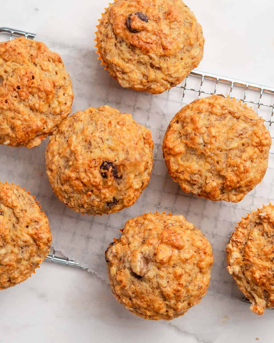 Birds eye view of 7 banana carrot muffins on a wire rack.
