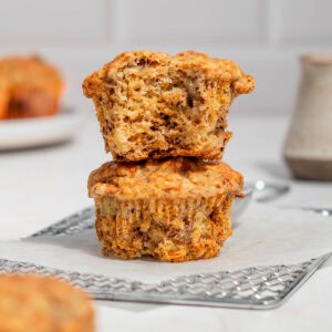 Stack of 2 banana carrot muffins on a wire rack.
