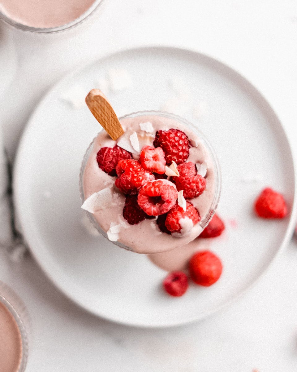 Birds-eye-view of this berry smoothie topped with fresh raspberries and coconut flakes.