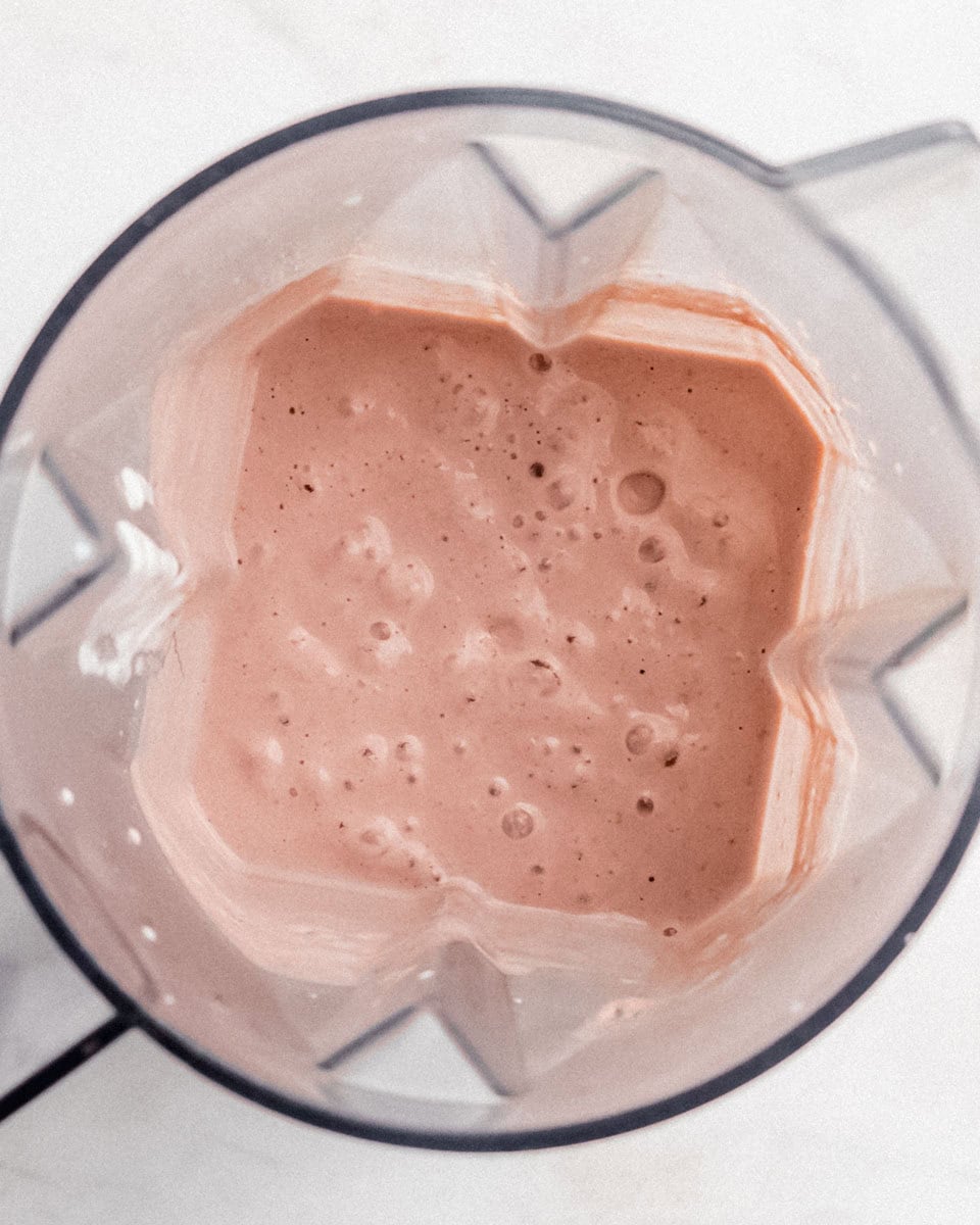 Bird's-eye view of a freshly blended berry protein smoothie inside a blender.
