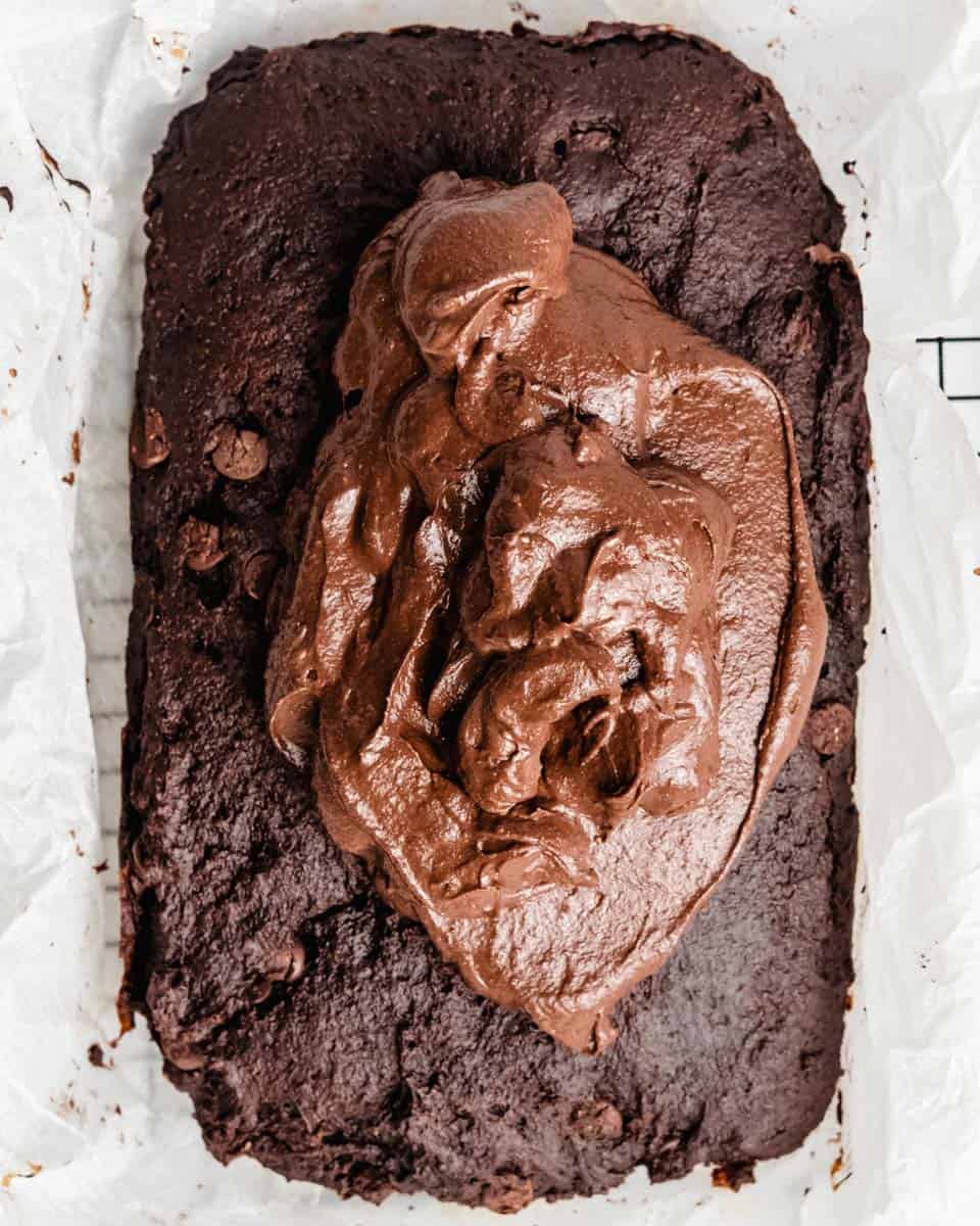 Baked chocolate cake on a wire rack with ganach added on top.
