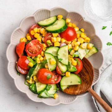 Birds-eye-view of this salad in a bowl. Next to it a glass of water and a linen napkin.