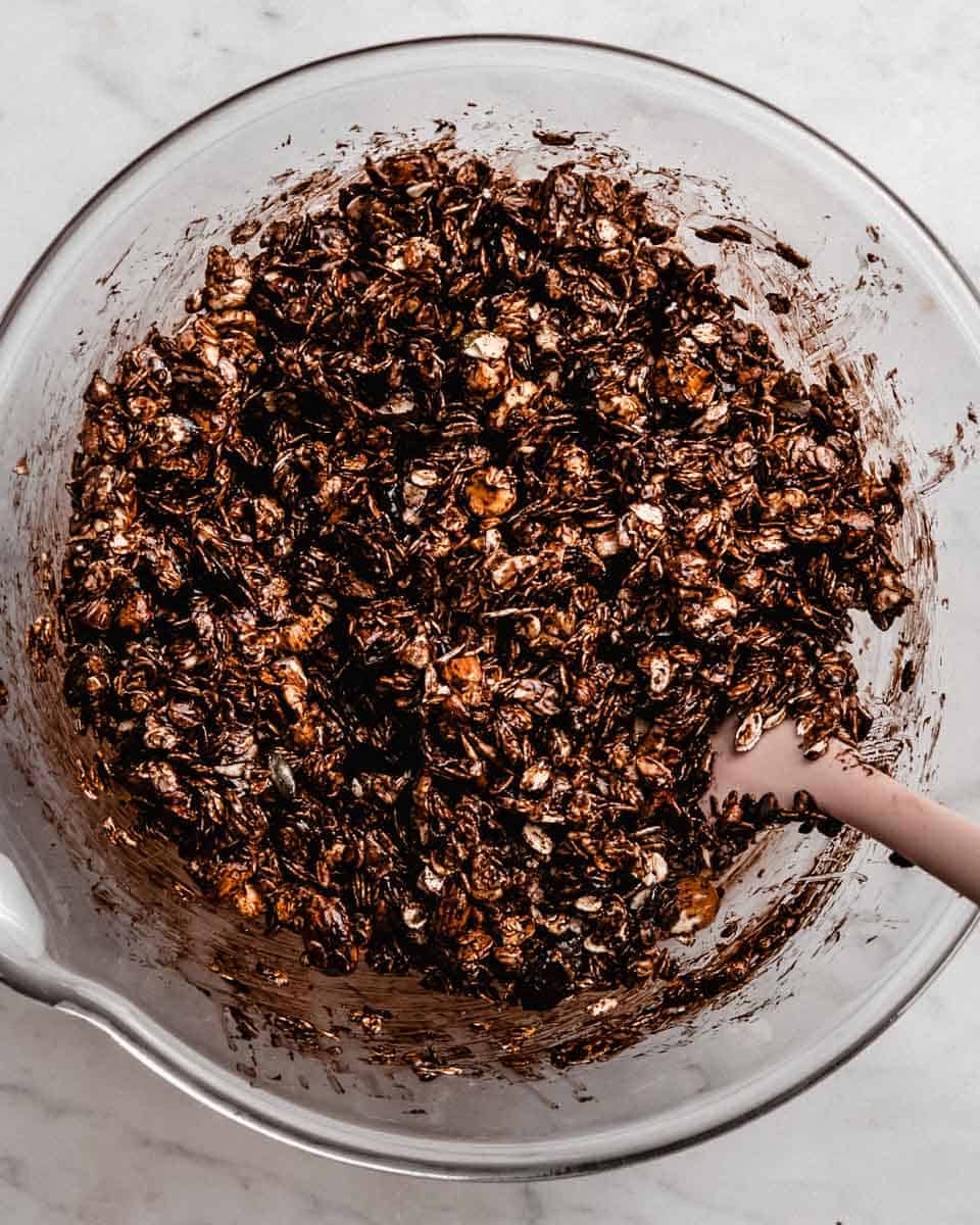 Wet and dry granola ingredients whisked together in a bowl.