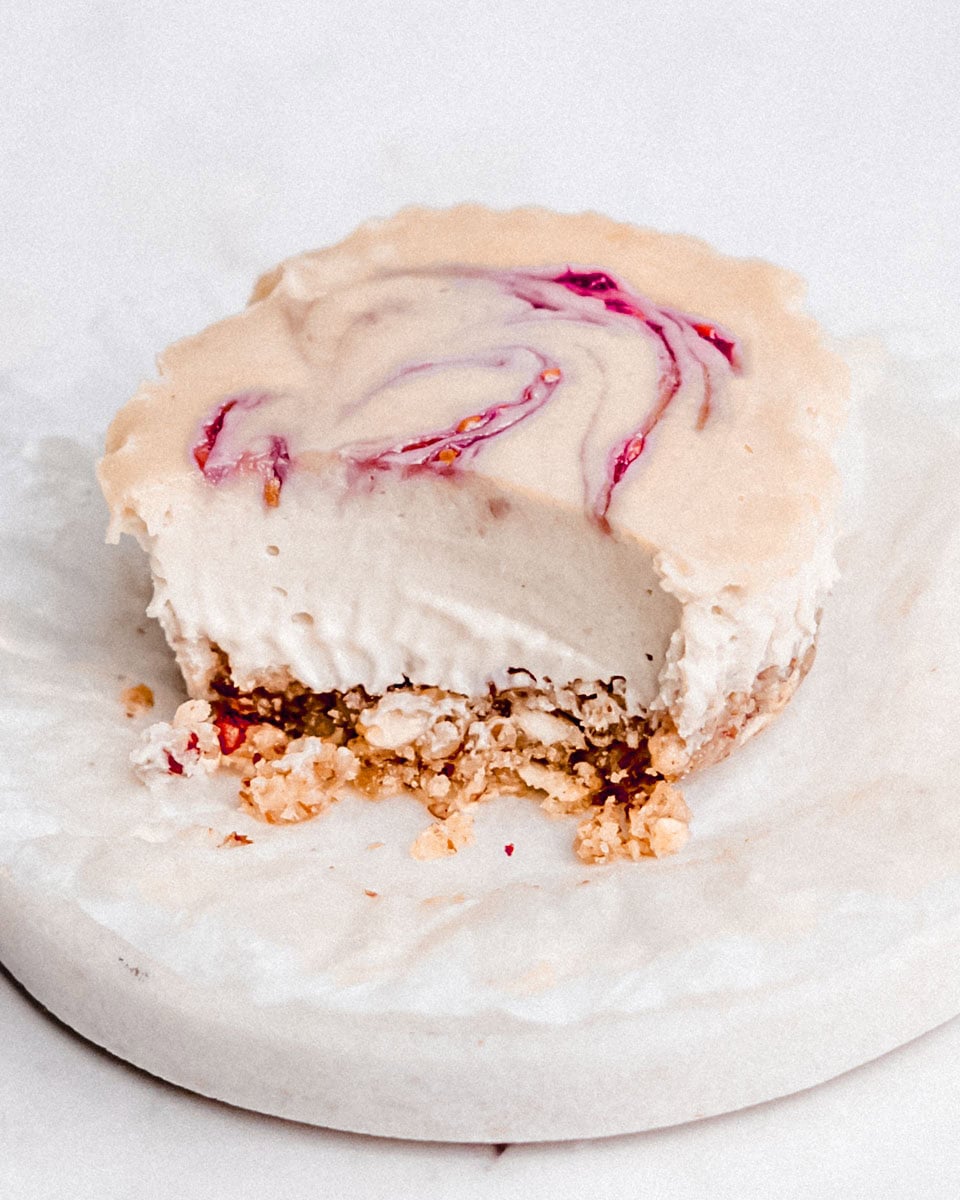 A creamy mini vegan cheesecake with a spoonful taken out, showing its smooth texture.