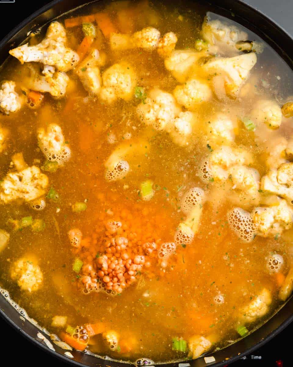 All the veggies, spices, red lentils and veggie broth in a pan.