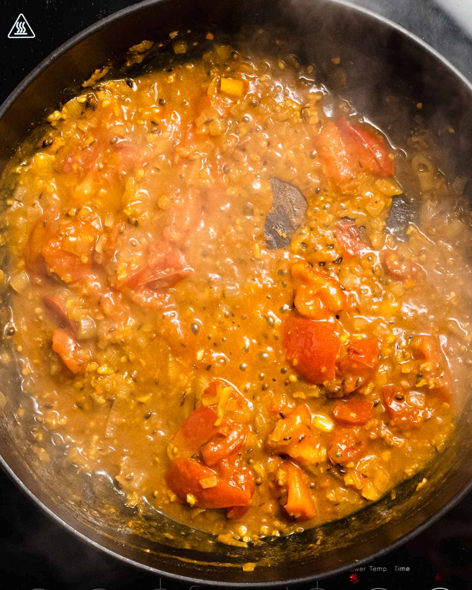 Onion, spices, ginger, garlic and tomatoes simmering in a pan.