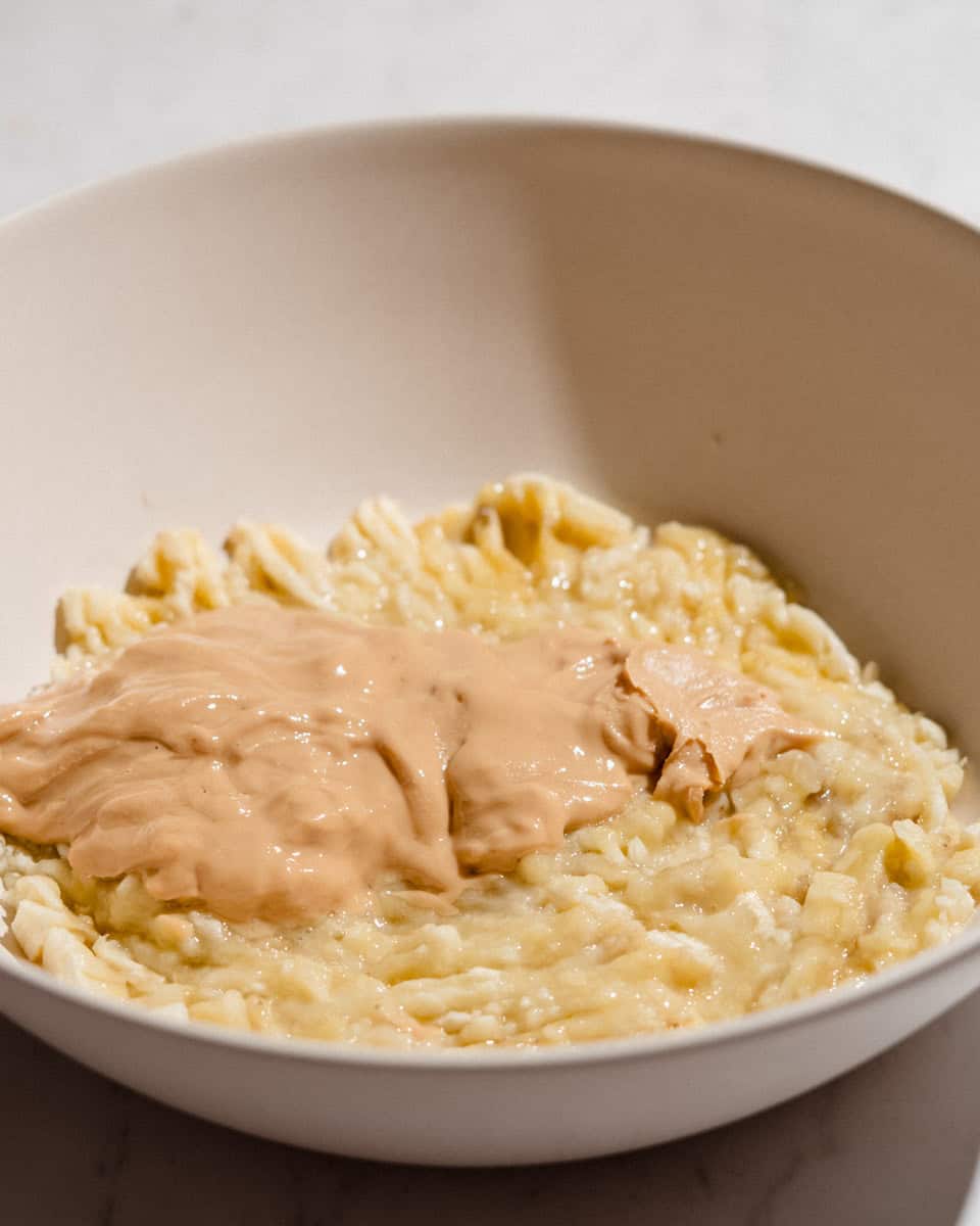 Mashed ripe bananas and creamy peanut butter in a white mixing bowl.