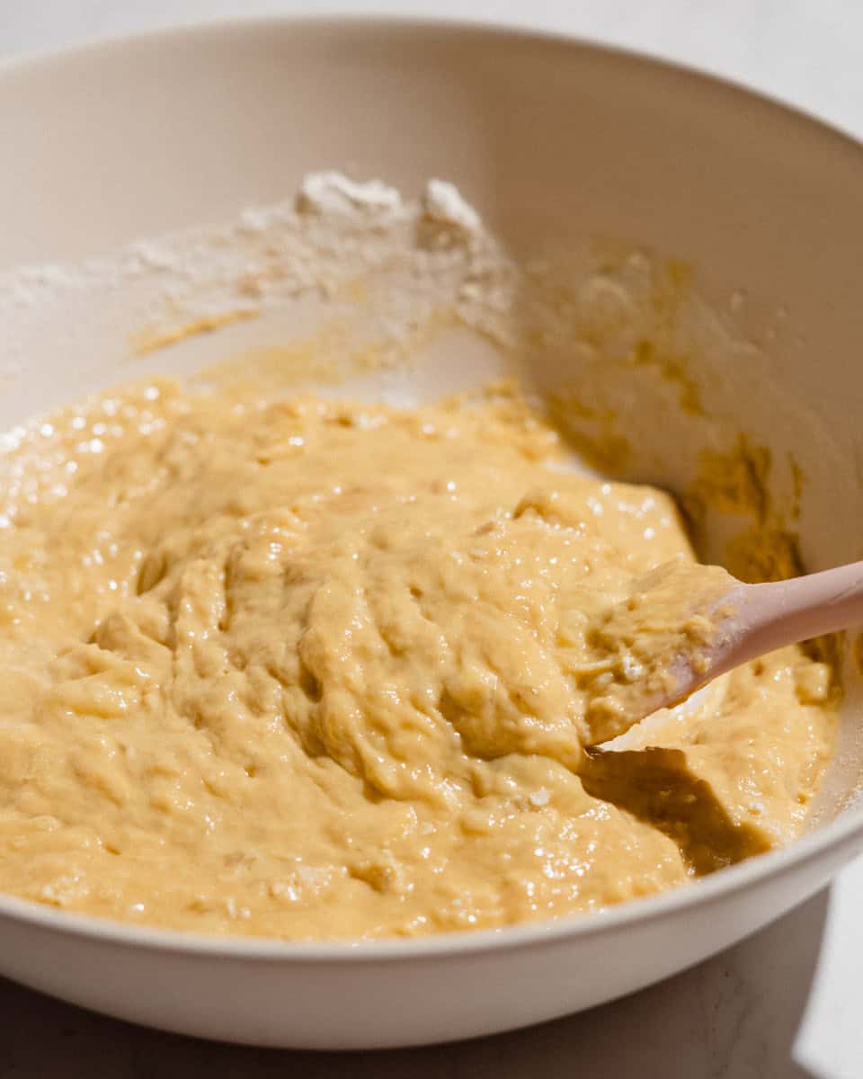 Flour being folded into the peanut butter banana bread batter with a spatula.